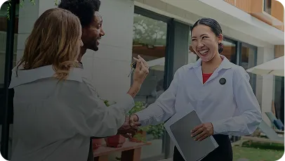 Real estate agent shaking hands with clients outside a home